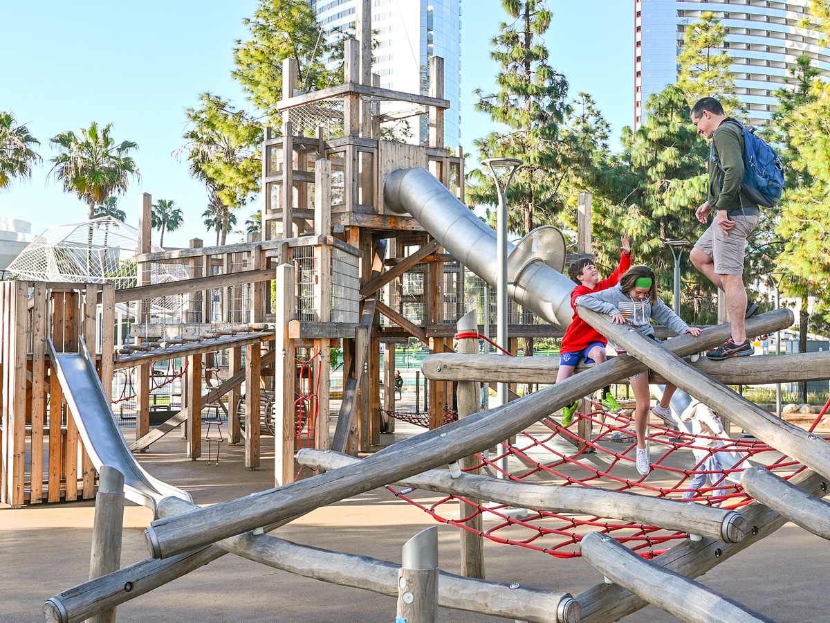 Outdoor play area, climbing structure in the front, play tower with tunnel slide, bridge crossing and slide behind it © Daniel Perales