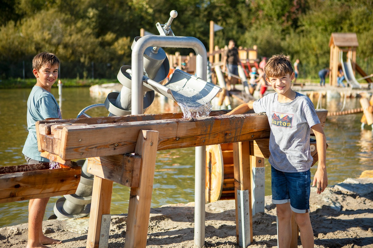Kinder spielen an einer Archimedischen Schraube und Wasserrinnen aus Holz am Bostalsee.