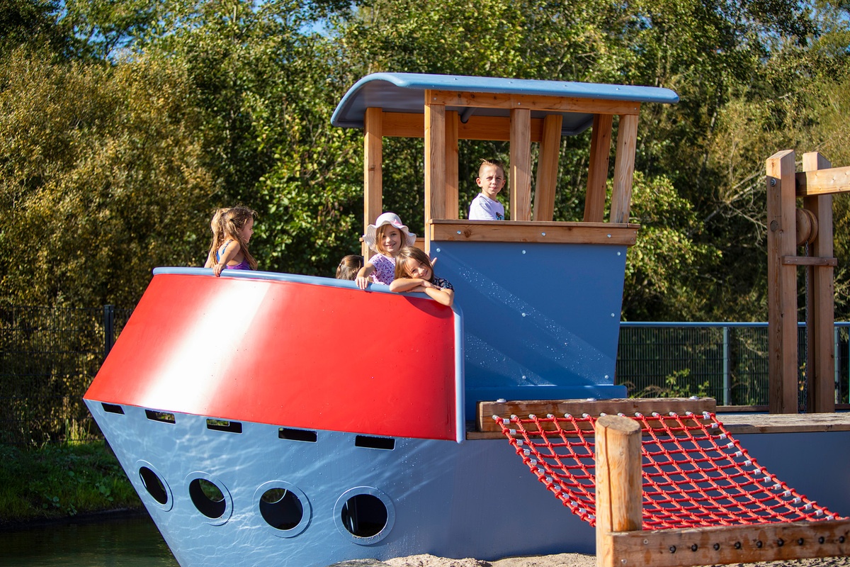 Kinder spielen auf einem blau-roten Metallschiff. 