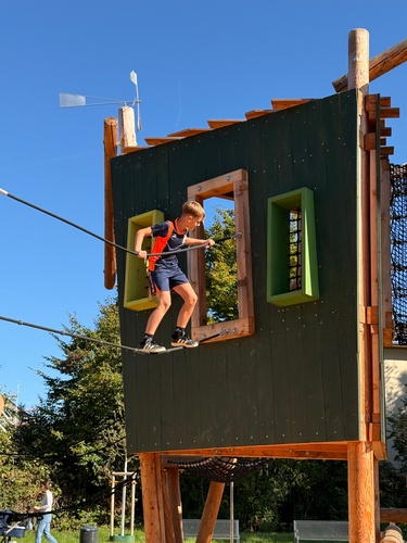 Child balances on a climbing rope to reach a play box on the ‘Skywalk’ climbing frame. 