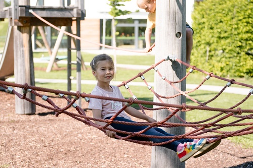 Child sitting relaxed in a horizontal triangular net above the ground.