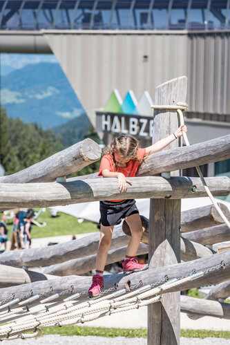Child climbing on a climbing structure made of robinia wood.