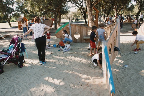 Kinder spielen an einer Raupe Variante 01 aus Holz im Sand