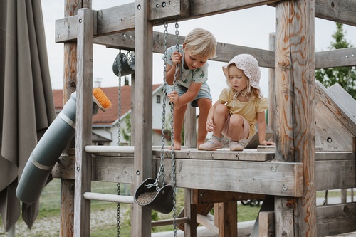 Two children playing on the building site with sand hoist.