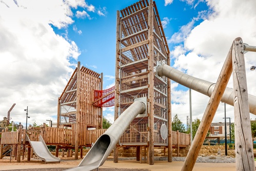 Two towers connected by a red suspension bridge with tunnel slides.  